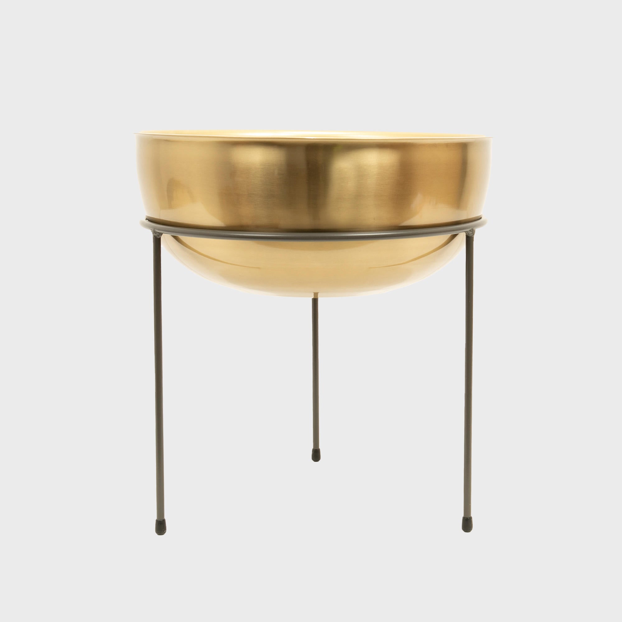 A matte brass bowl on a metal riser is displayed against a white background.