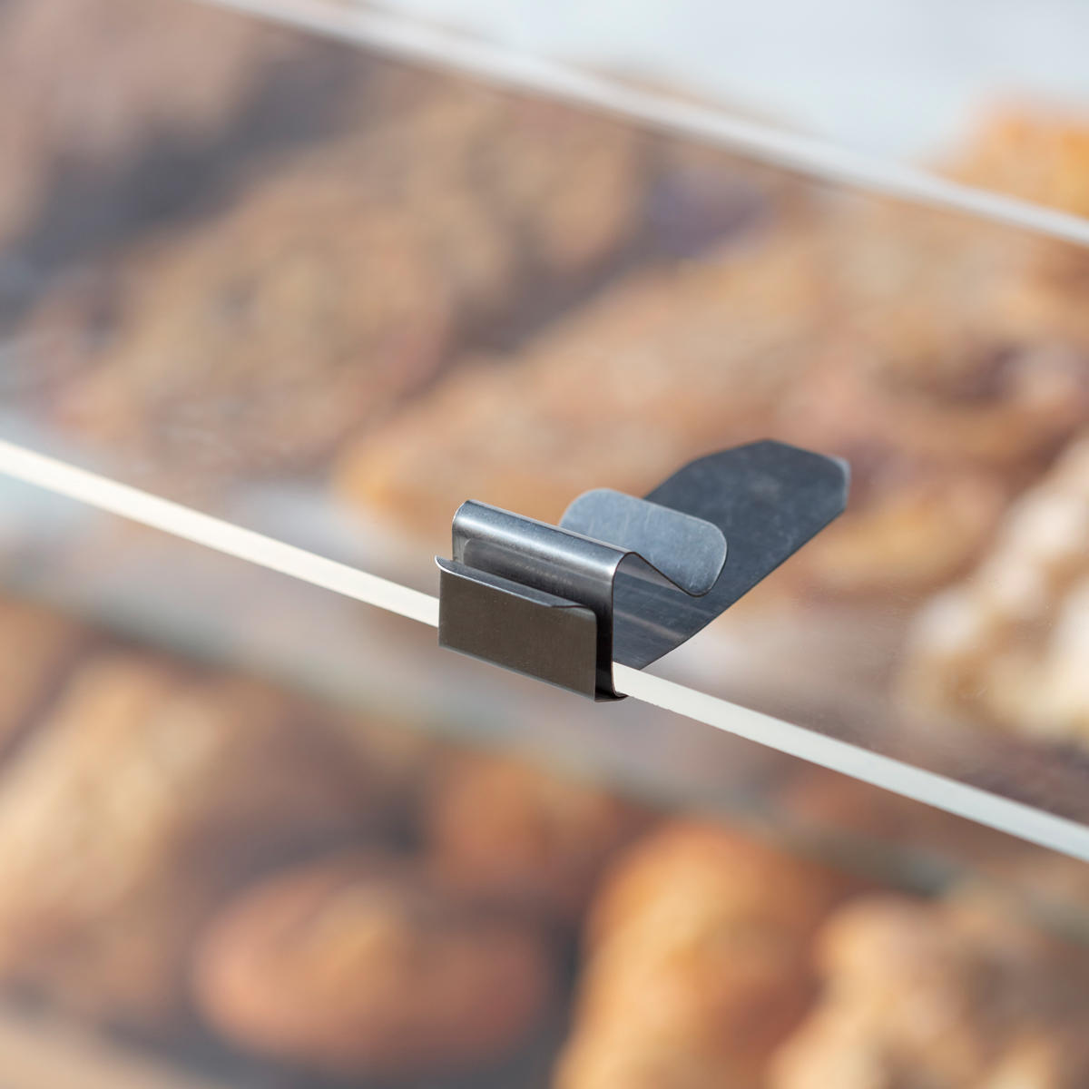 Metal shelf edge ticket holder with a clean surface for visible retail messaging.